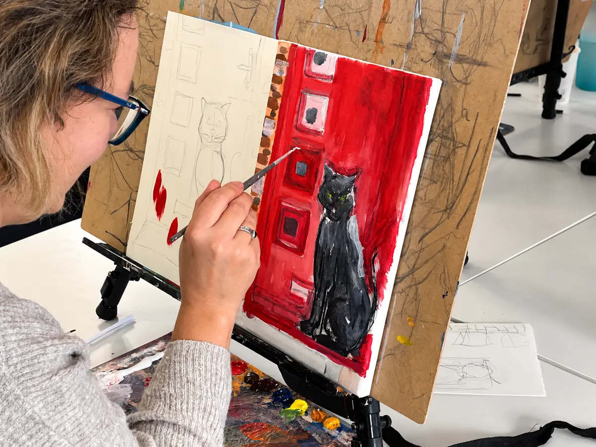 Participant painting a black cat against a red background