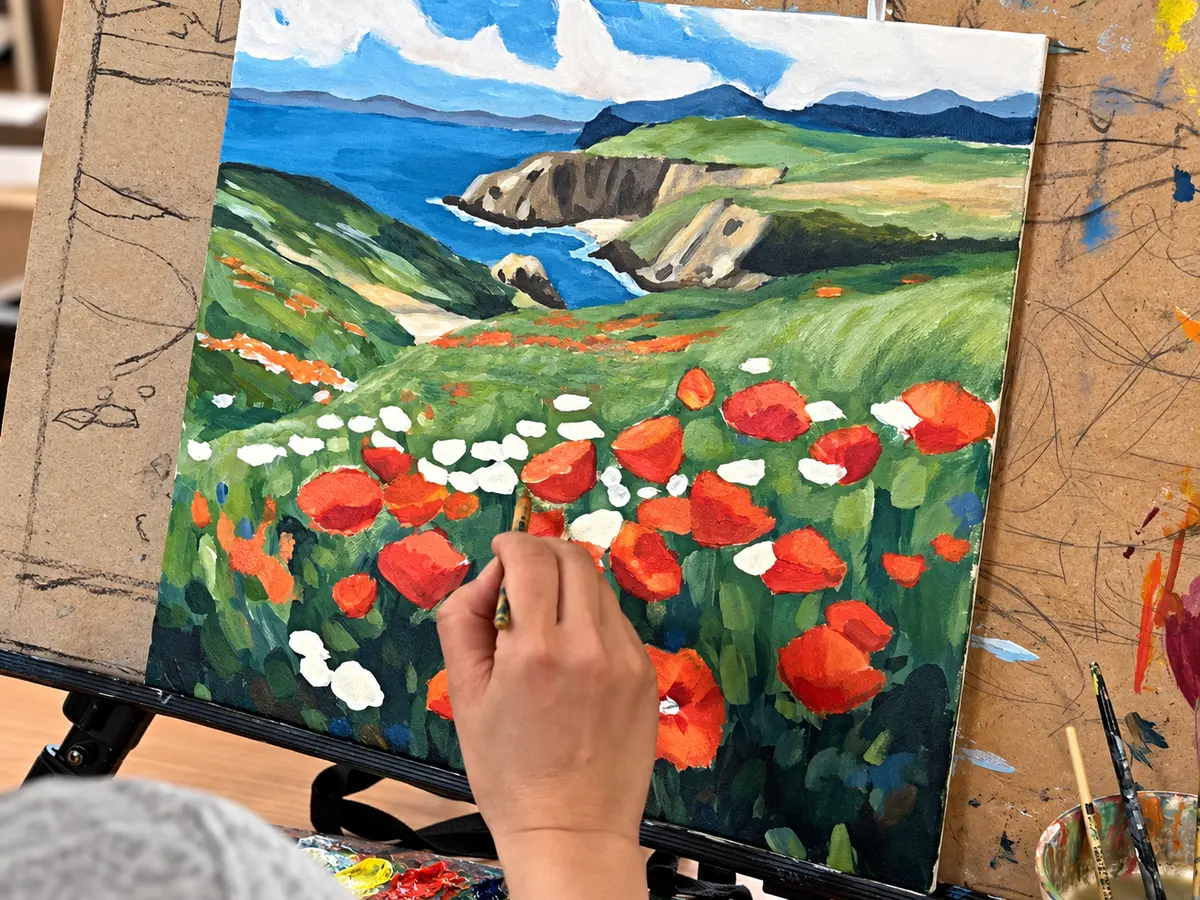 Participant painting a coastal landscape with poppies